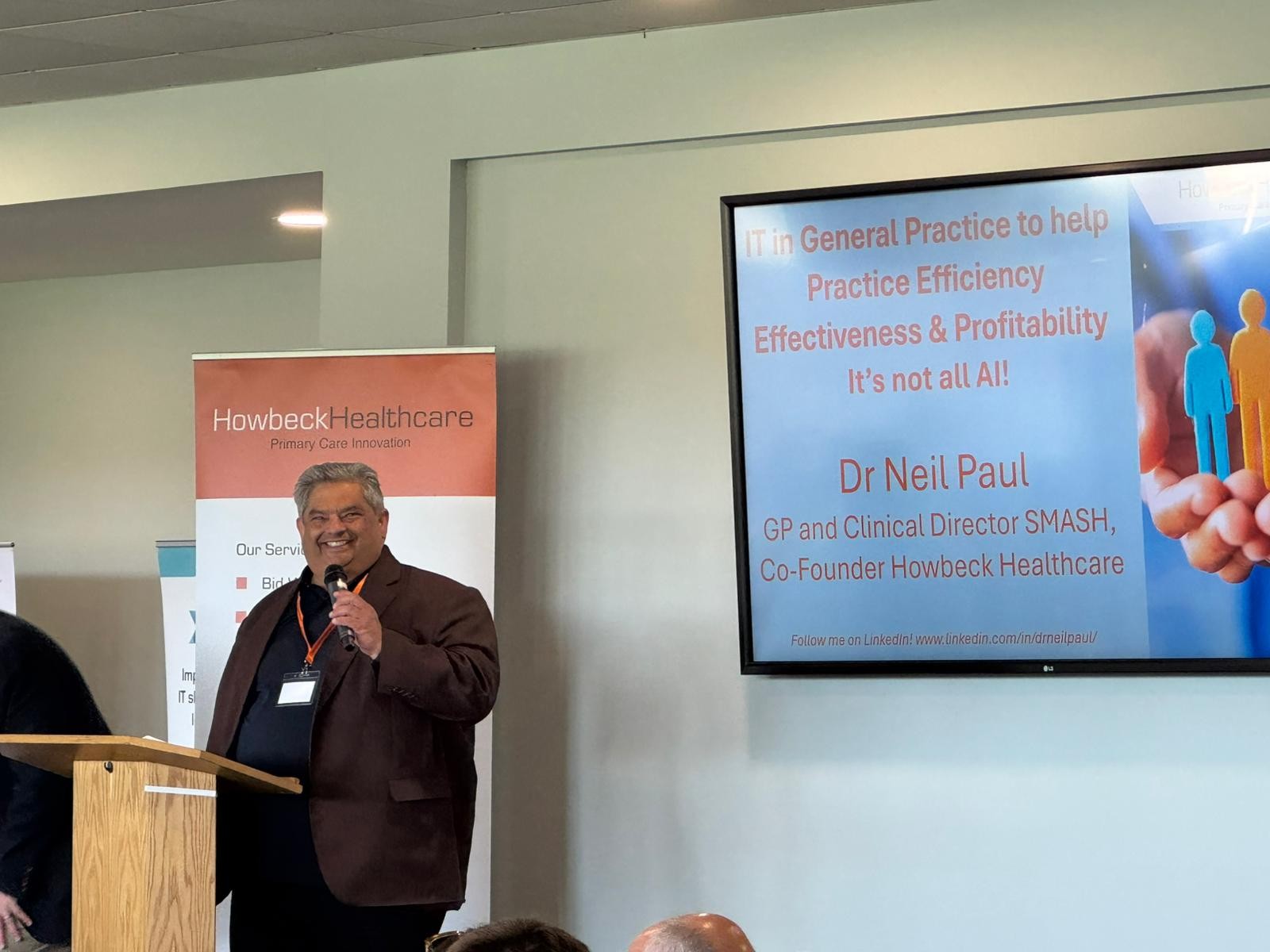 Dr Neil Paul stood on stage in a dark suit addressing the room.
