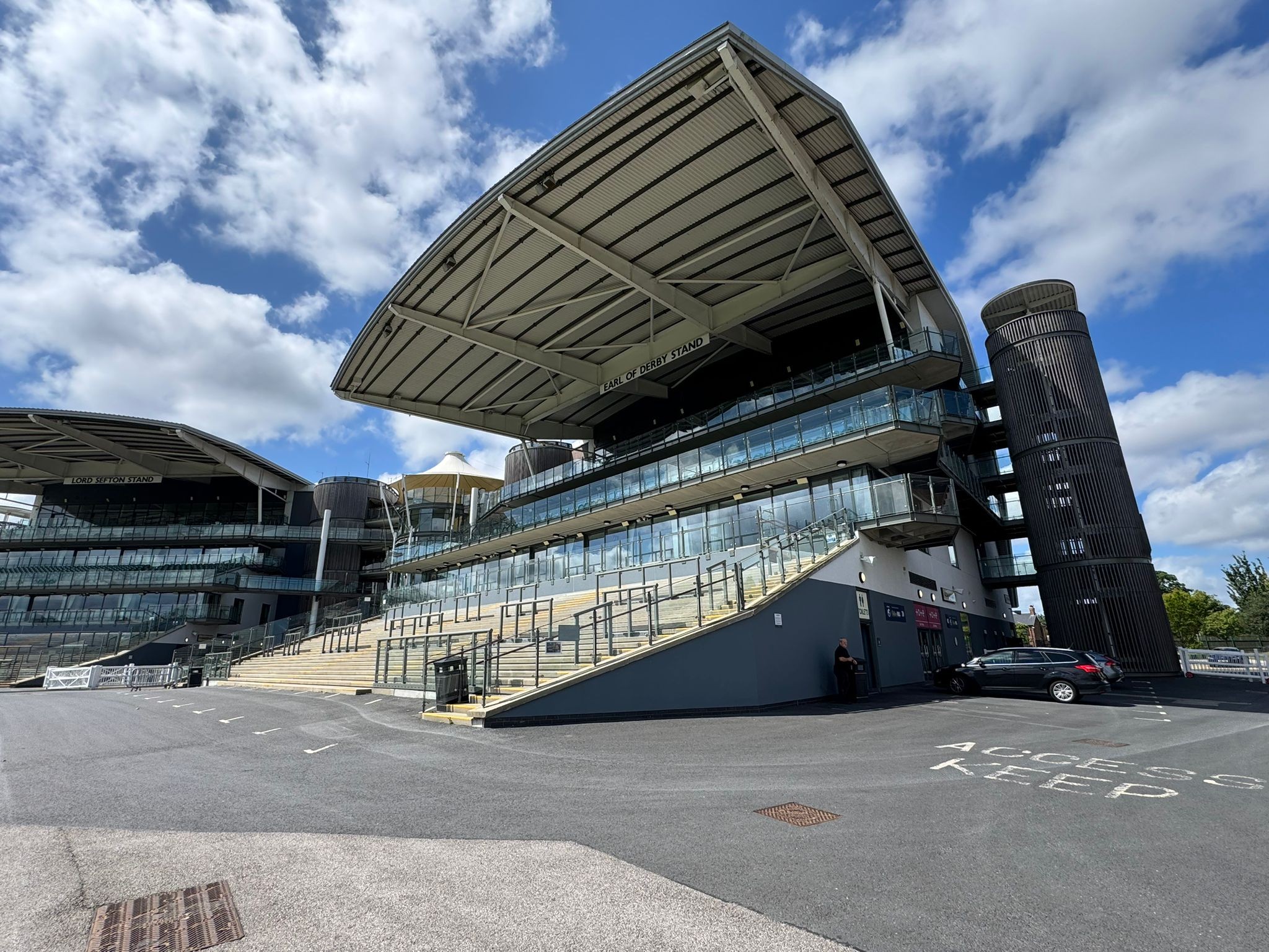 An outside image of a stand at Aintree Race course on a cloudy but sunny day.
