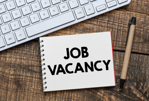 A desk with a computer keyboard and notepad on. The notepad states Job Vacancy.